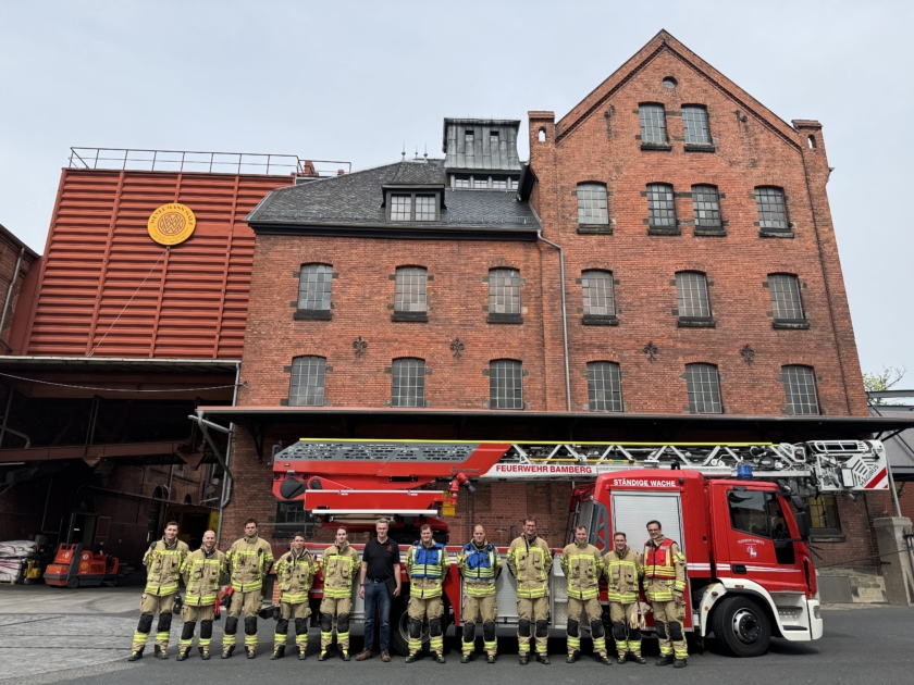 Gruppenbild der Feuerwehr in Montur mit Weyermann Mitarbeitenden vor Weyermann Gebäude und Feuerwehrauto